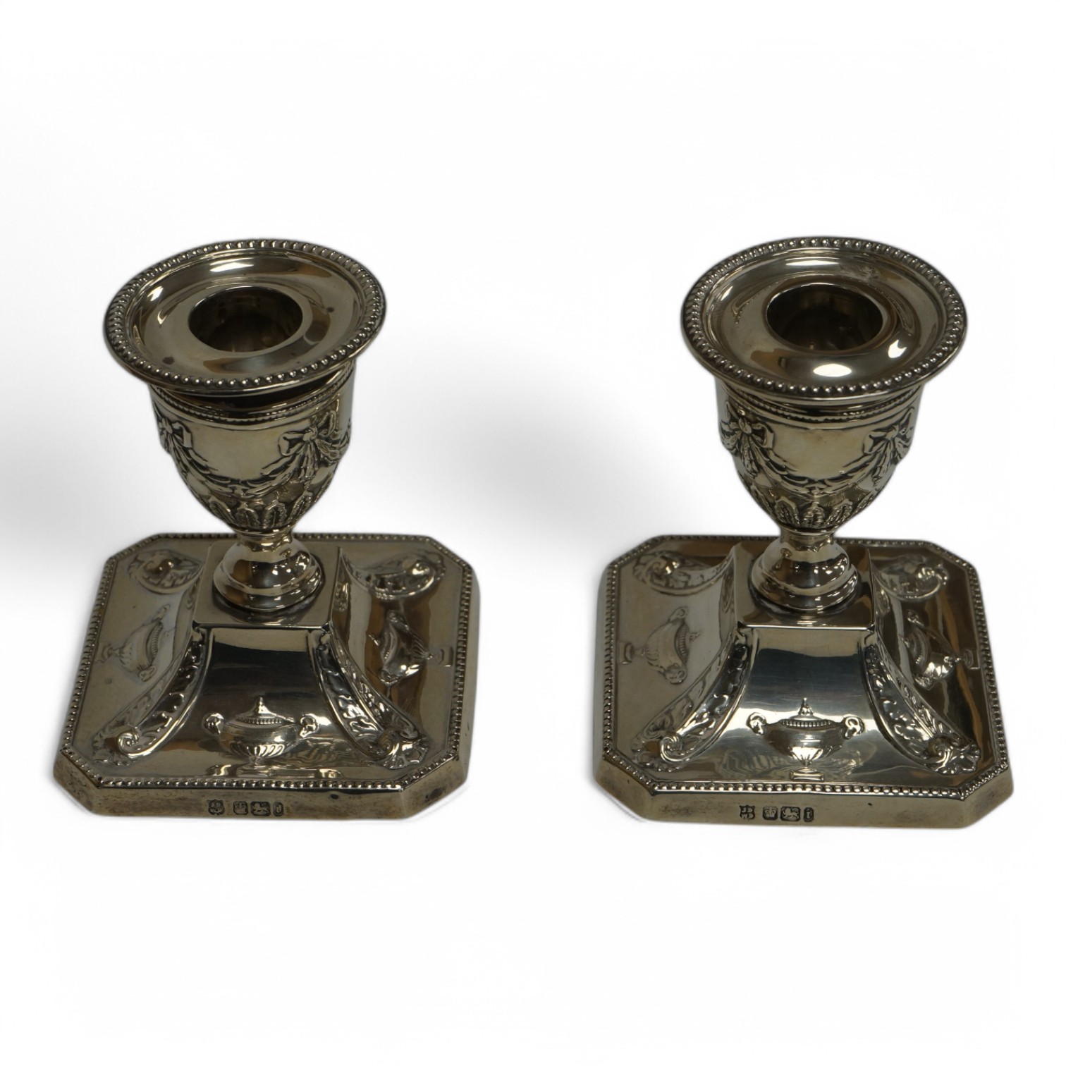 A pair of Edwardian silver mounted dwarf candlesticks, with swag and ribbon decoration, by James Deakin & Sons, Sheffield, 1901, height 92mm, weighted. Condition - poor to fair